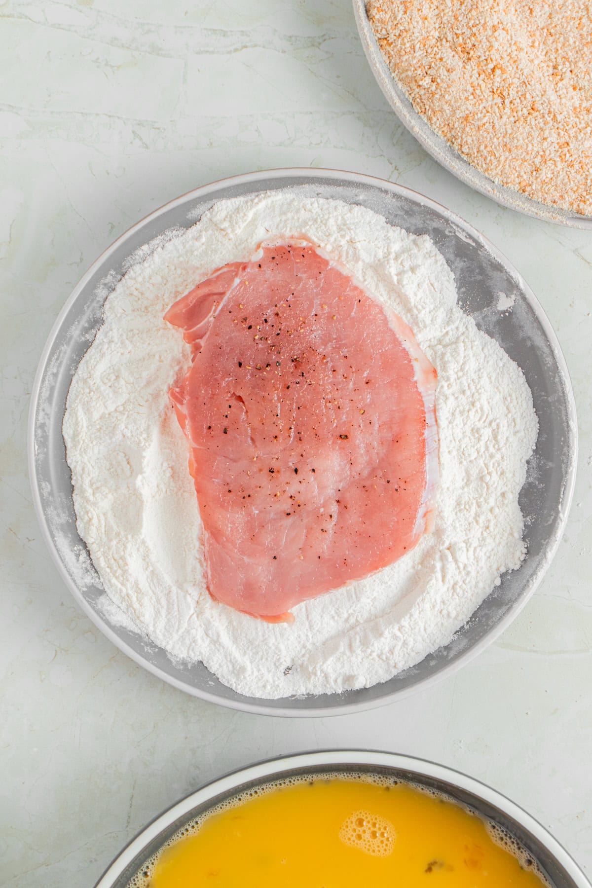 Coating pork chop with flour.