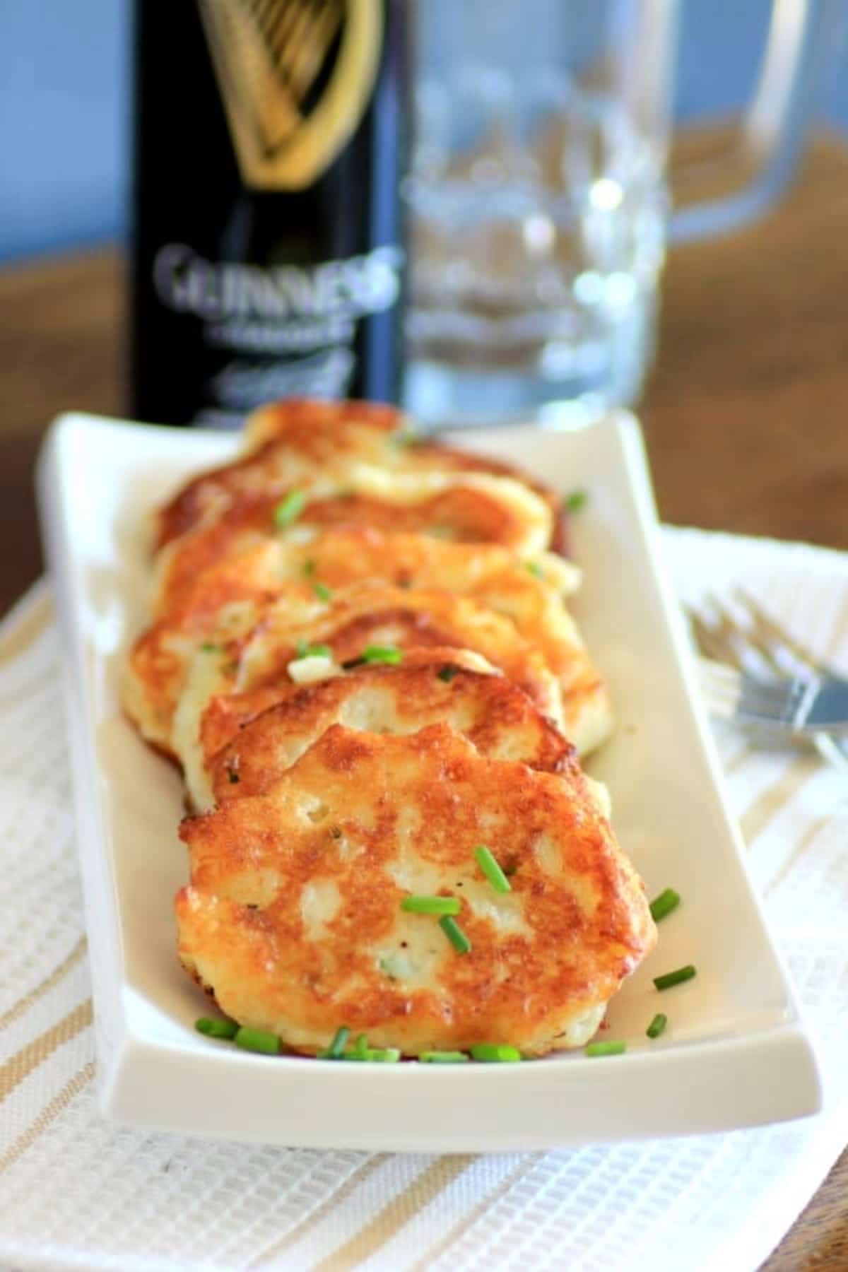 Potato Pancakes served in a row on a white dish with guinness.