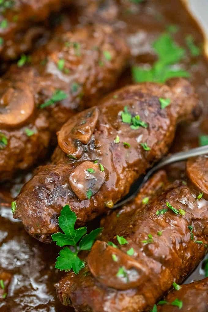 Beef rouladen roll being served with a silver spoon