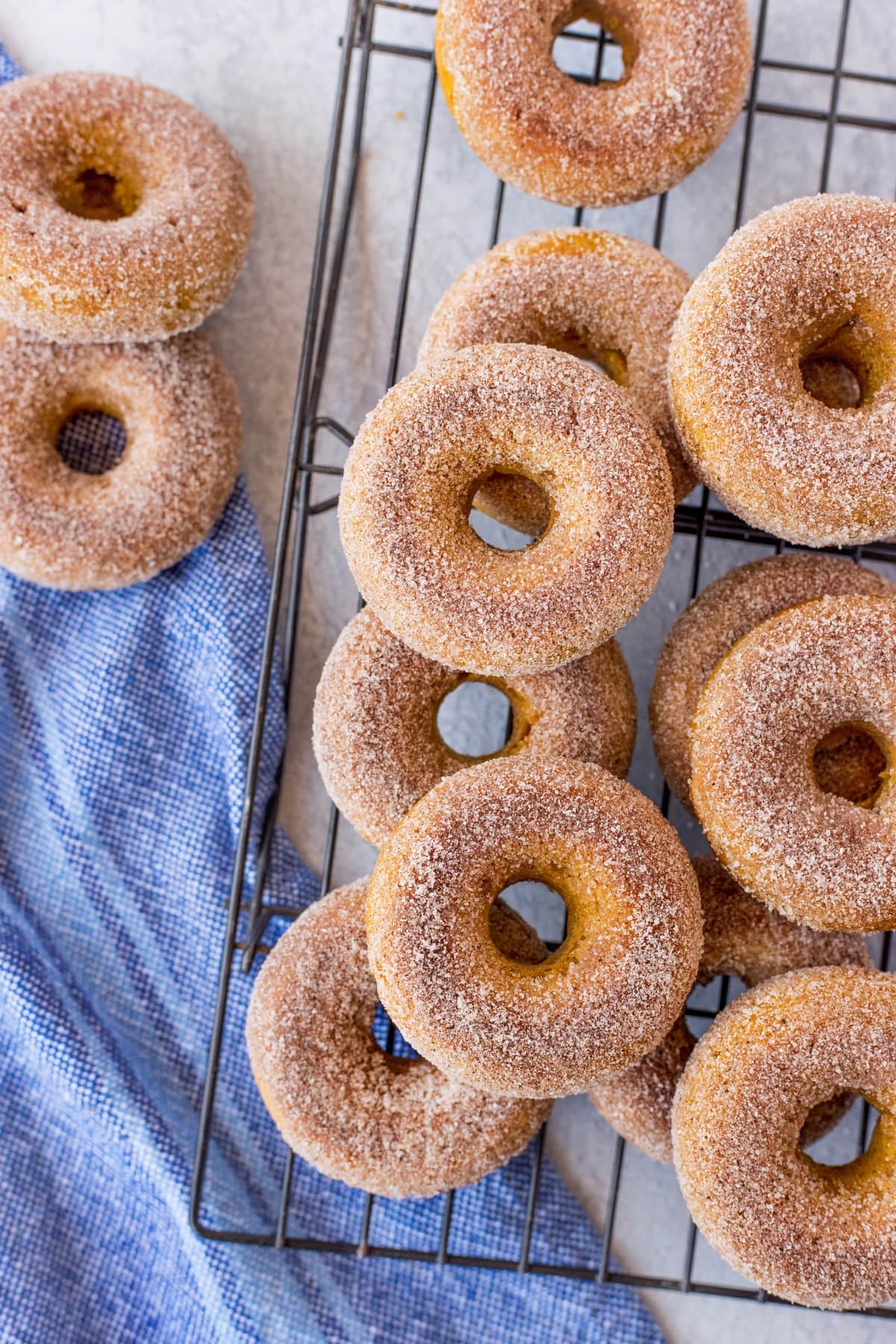 Overhead shot of pumpkin donuts on a cooling racked stacked on each other. 