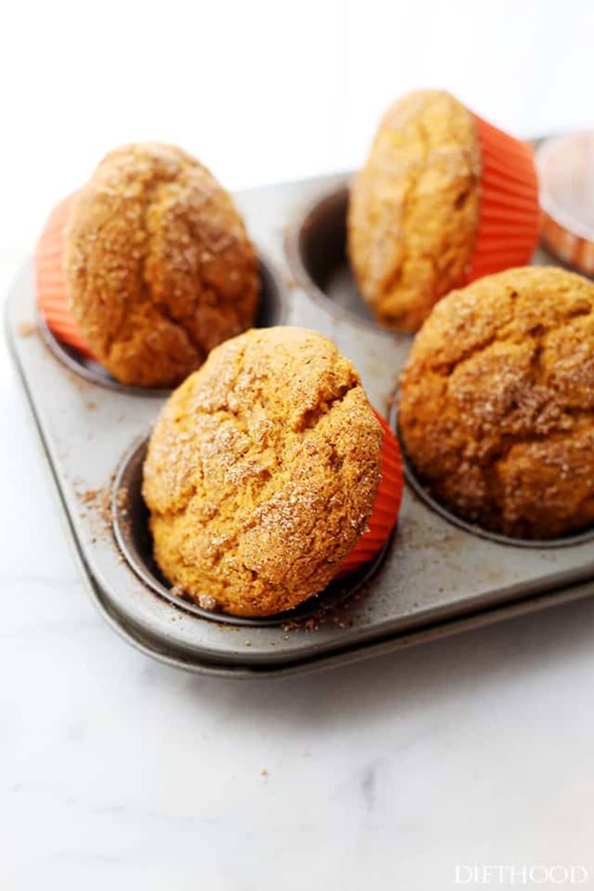 Pumpkin muffins being removed from a muffin pan. 