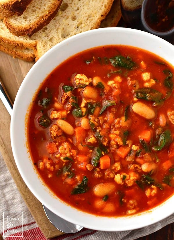 Italian Sausage, Spinach, Tomato Soup in a white bowl with bread