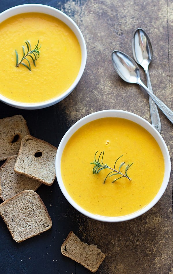  Two bowls Carrot Ginger Soup in white bowls with spoons on the side