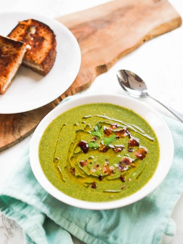 Spinach Apple Soup in a white bowl with a plate of toast