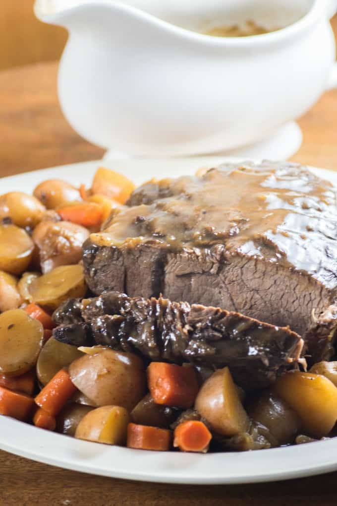 Cooked pressure cooker roast beef on a platter with gravy boat