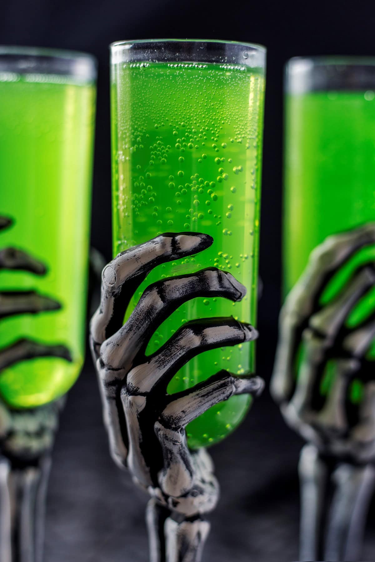 Skelton hand holding a green Enbalming fluid cocktail. 