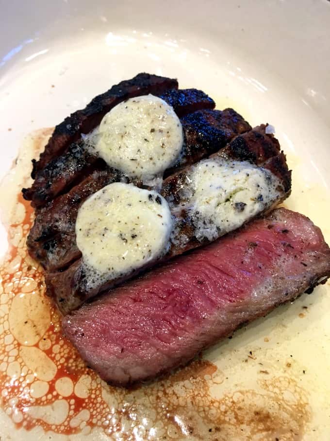 Medium rare steak with truffle butter on a white plate