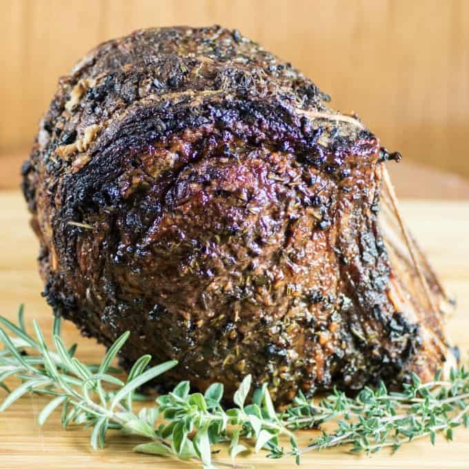 Roast Beef on a wooden cutting board with fresh herbs