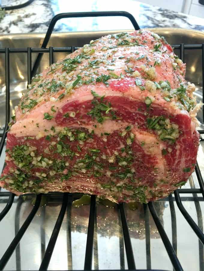 Uncooked prime rib with a herb rub in a roaster