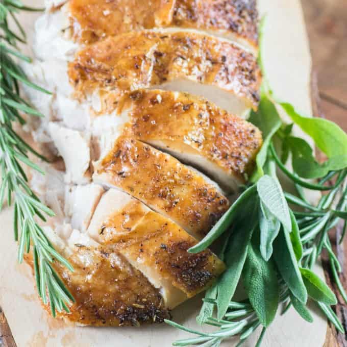 Sliced roast turkey on a board with fresh herbs