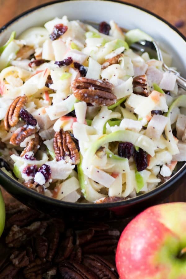 Spiralized apple turkey slaw in a bowl with an apple and pecans 