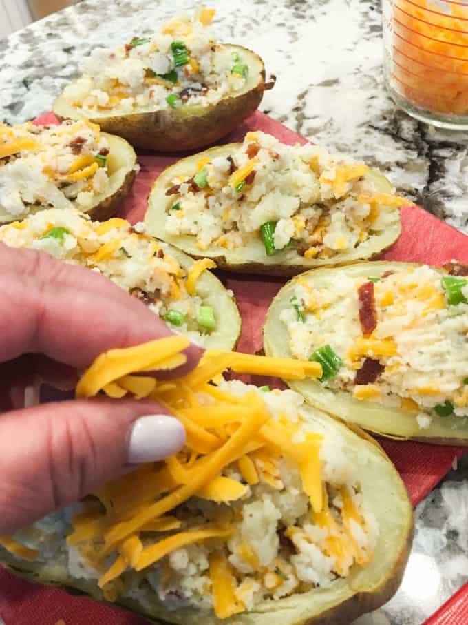 Putting on cheese on the Stuffed Baked Potatoes.