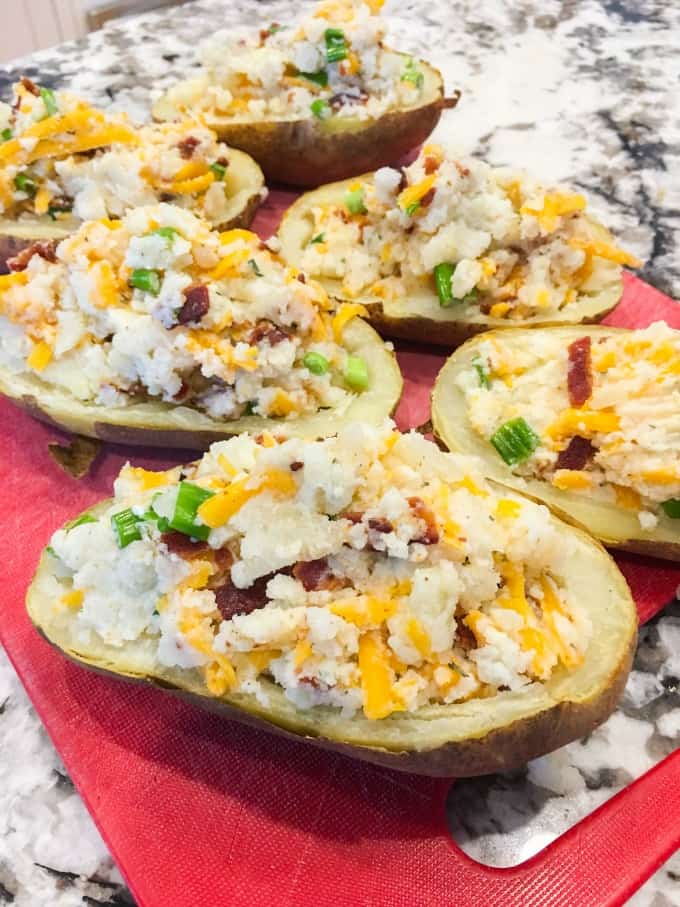 Stuffed Baked Potatoes without cheese on top on a red cutting board. 