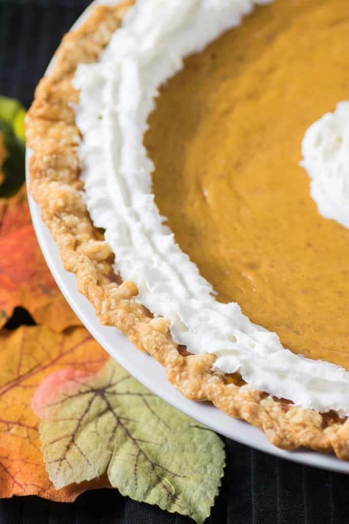 Super Easy Pumpkin Pie Recipe in a white dish with scattered leaves