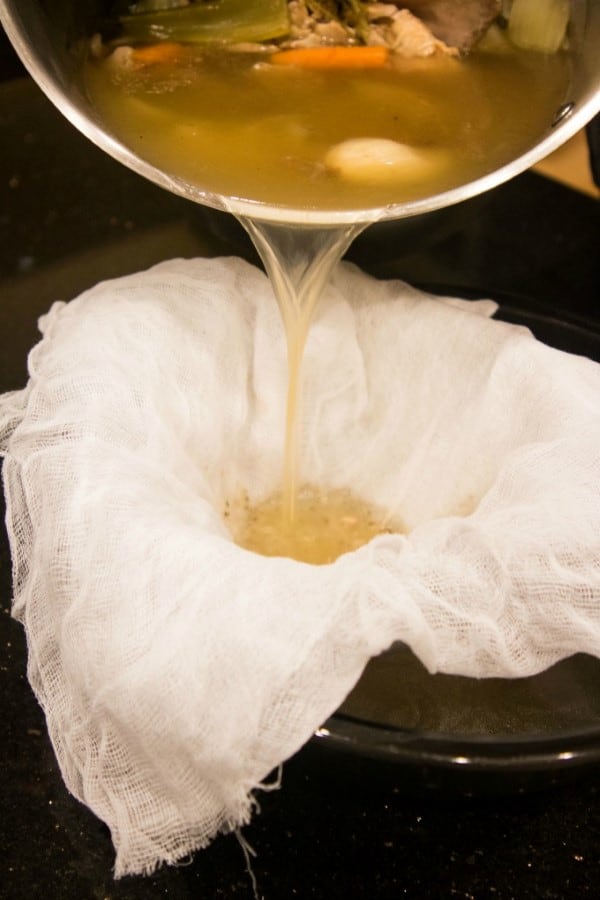 Turkey broth being poured through cheese cloth