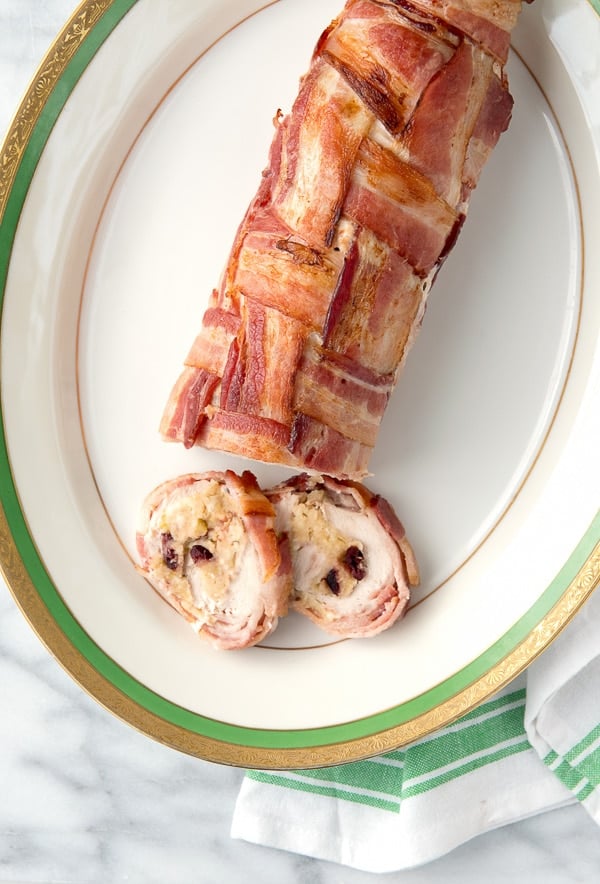 Turkey roulade criss-crossed wrapped in bacon on a platter