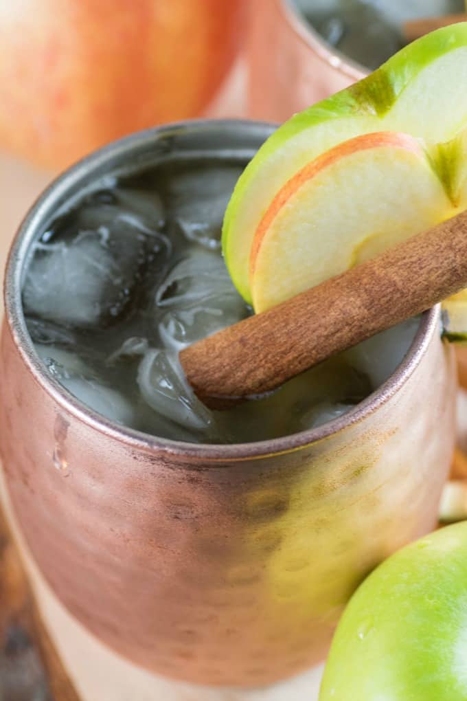 Close up of a Apple Bourbon Moscow Mule in a copper mug with apple slices. 