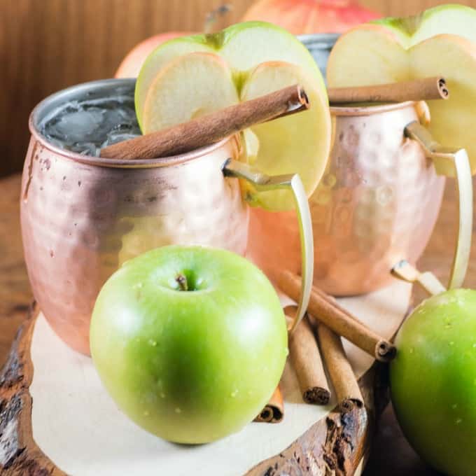 Apple Bourbon Moscow Mule in a copper mug with apple slices. 