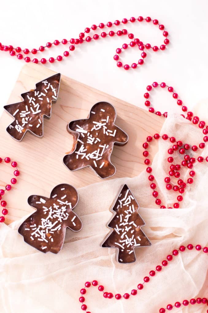 Cookie Cutter Christmas Fudge on a cutting board with red beads.