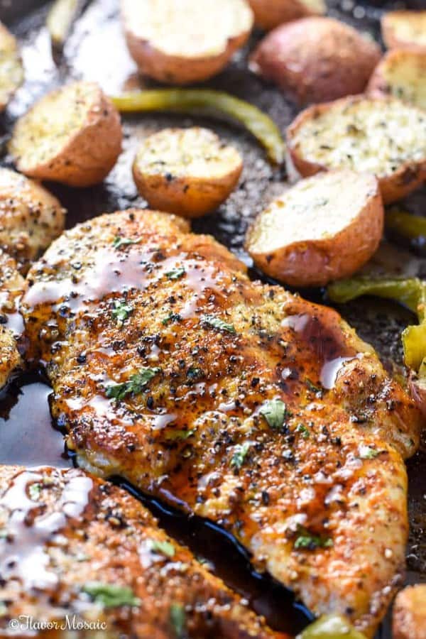 Juicy looking chicken with potatoes and peppers on a sheet pan