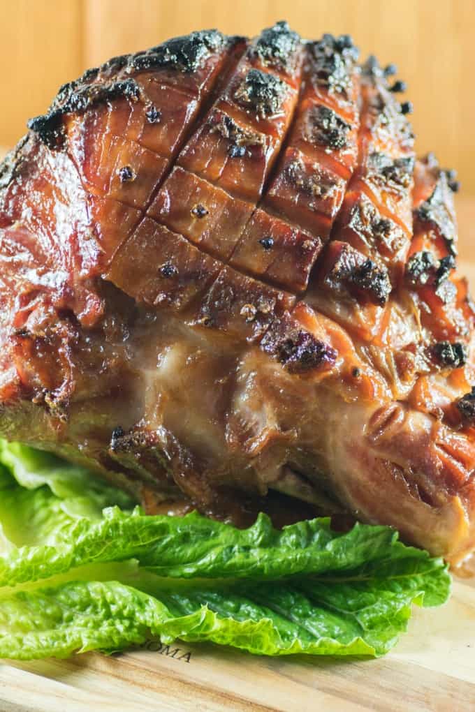 Glazed ham on a board with lettuce.