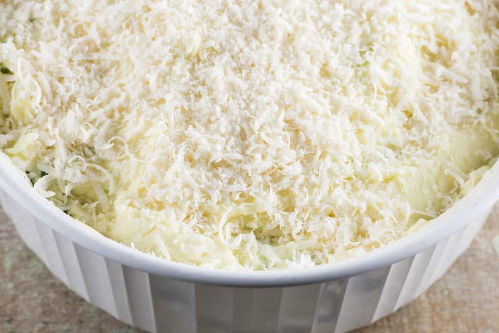 Make-Ahead Mashed Potatoes in a casserole dish with Parmesan cheeese