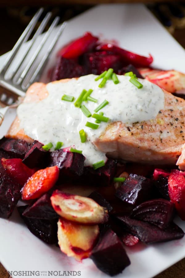 Salmon with horseradish sauce, beets and vegetables on a white plate with a fork