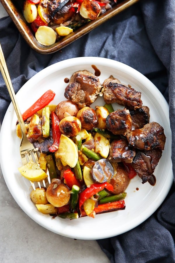 Steak tips and vegetables on a white plate with a fork