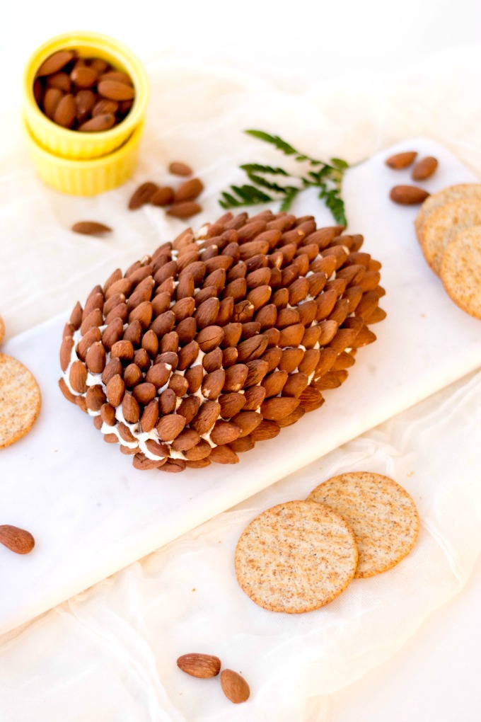Pine Cone Cheese Ball Recipe on a whitel board with crackers