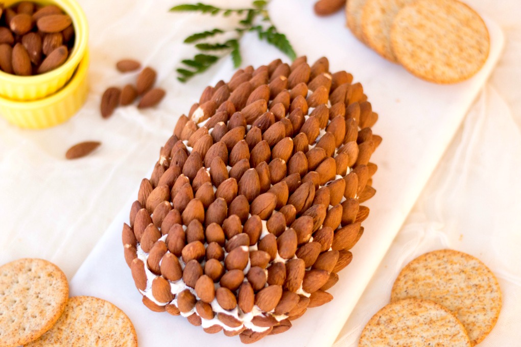 Pine Cone Cheese Ball Recipe on a whitel board with crackers