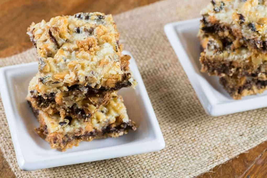 One Pan Magic Cookie Bars stacked on small white dishes