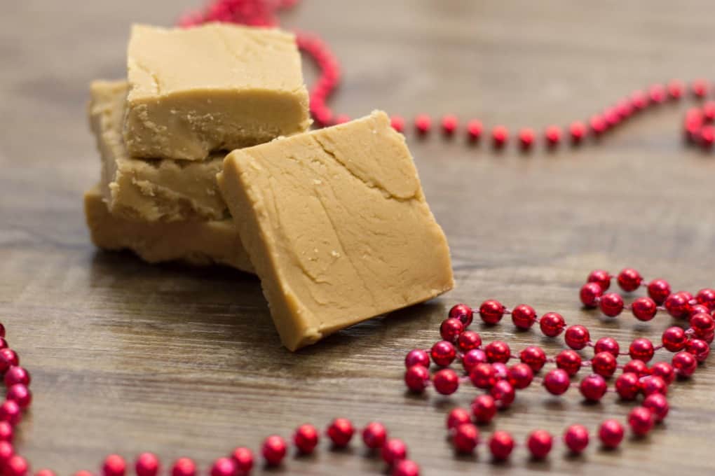 Easy Peanut Butter Fudge stacked up and on a board with red beads