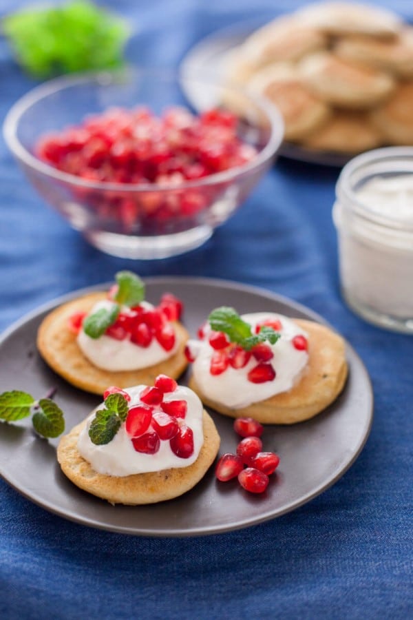 Chickpea pancakes appetizer with rosemary and pomegranate on a small black plate