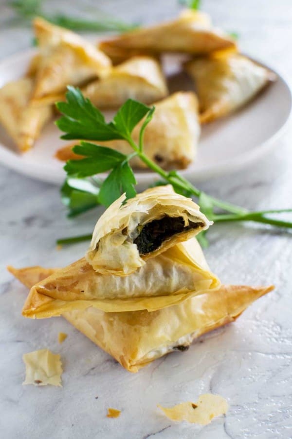 Crispy mushroom filo triangles on a white counter with a white serving tray in the background 