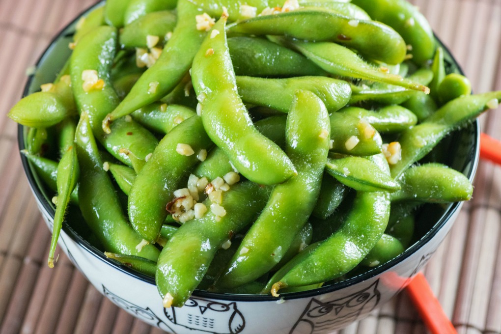 Spicy Edamane in a bowl with red chop sticks