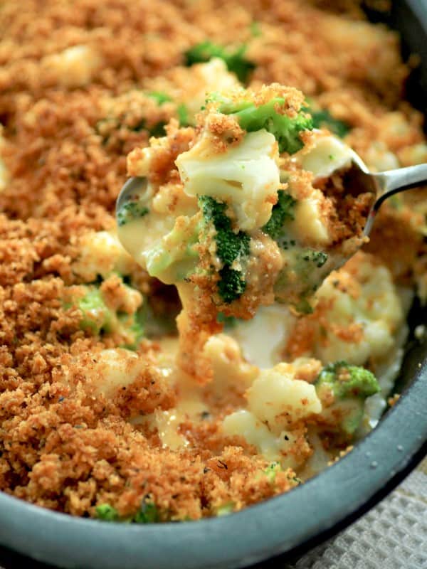 Broccoli cauliflower cheese bake in serving dish with a metal serving spoon