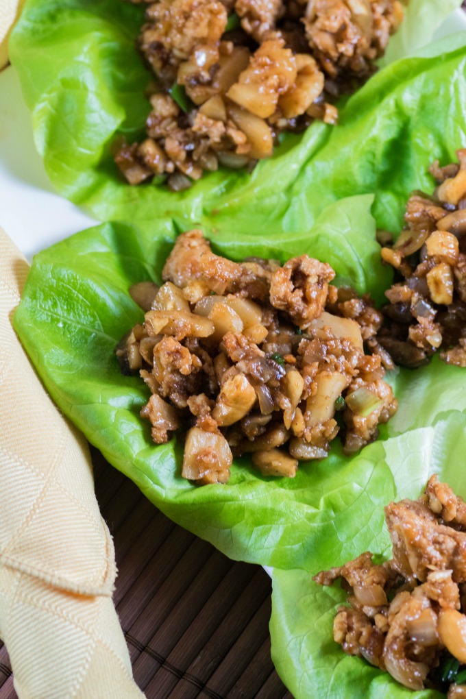 Chicken Lettuce Wraps on a platter on a brown placemat with a yellow napkin. 