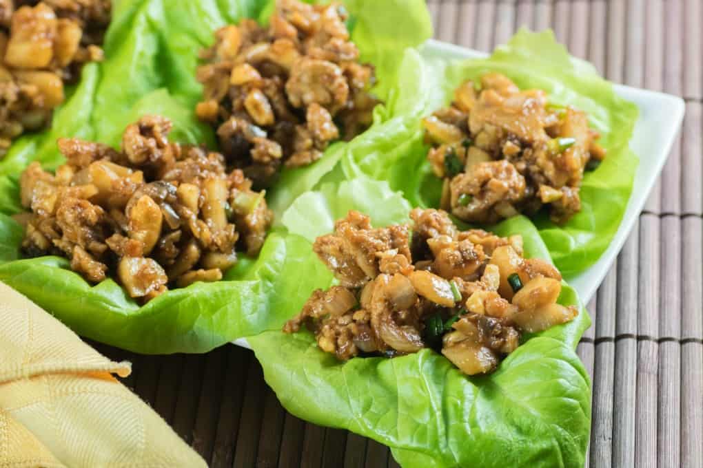 Chicken Lettuce Wraps on a platter on a brown placemat with a yellow napkin. 