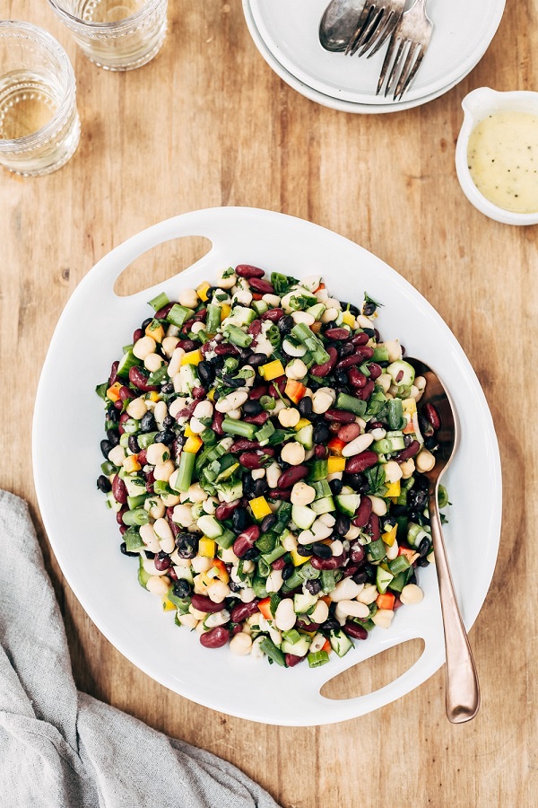 Five bean salad in a white serving bowl with a spoon