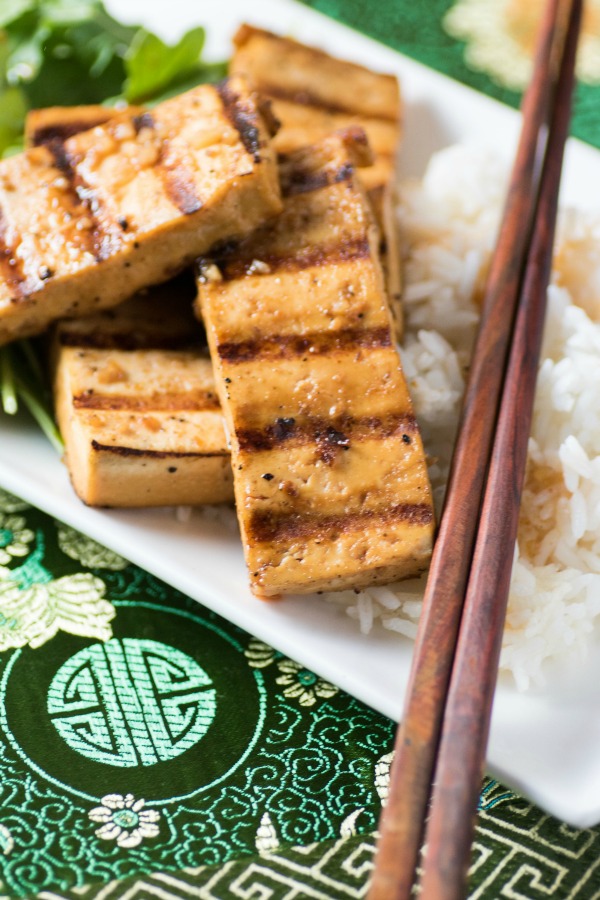 Marinated Grilled Spicy Tofu on a rice with chopsticks on a white platter