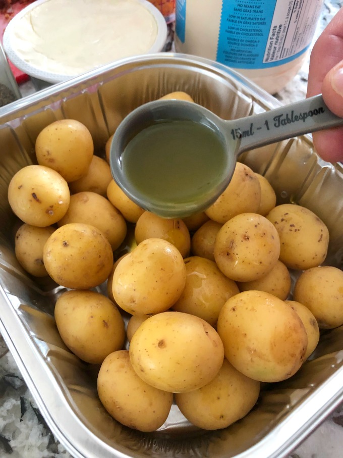 Olive oil being poured on Little potatoes