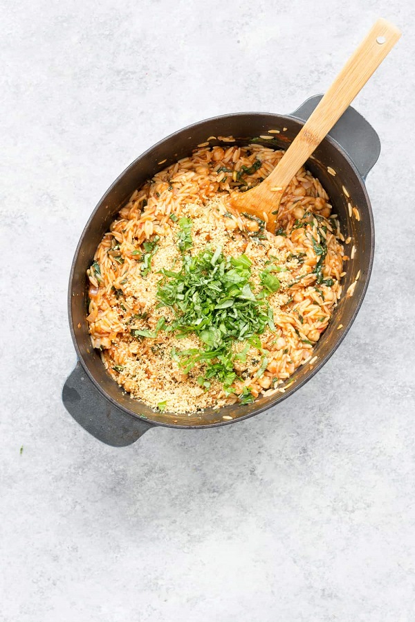 One Pot Tomato Orzo Pasta in a dutch oven with wooden spoon