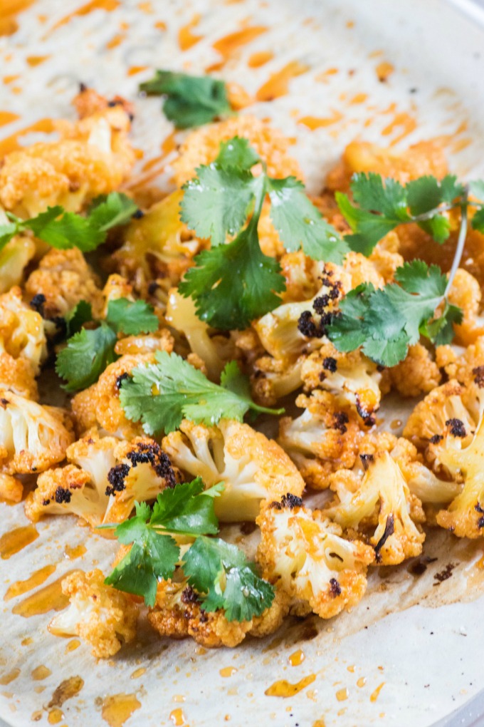 Sweet Sriracha Roasted Cauliflower piled high on a baking sheet with cilantro