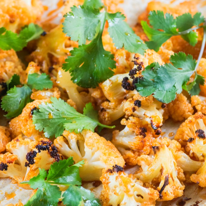 Sweet Sriracha Roasted Cauliflower on parchment paper with cilantro