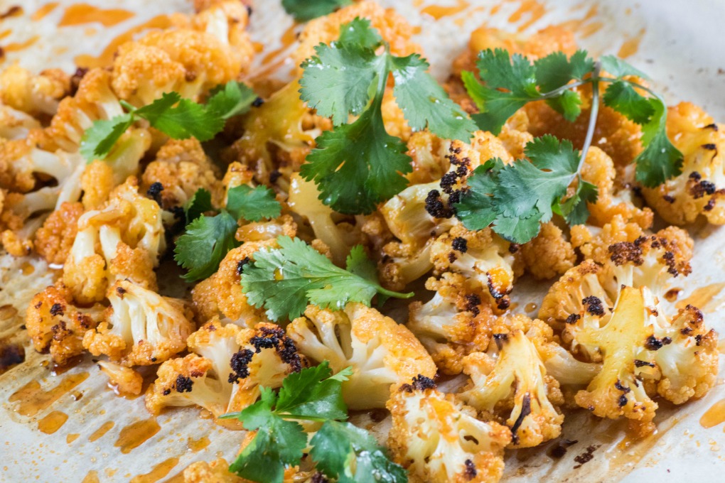 Sweet Sriracha Roasted Cauliflower piled high on a baking sheet with cilantro