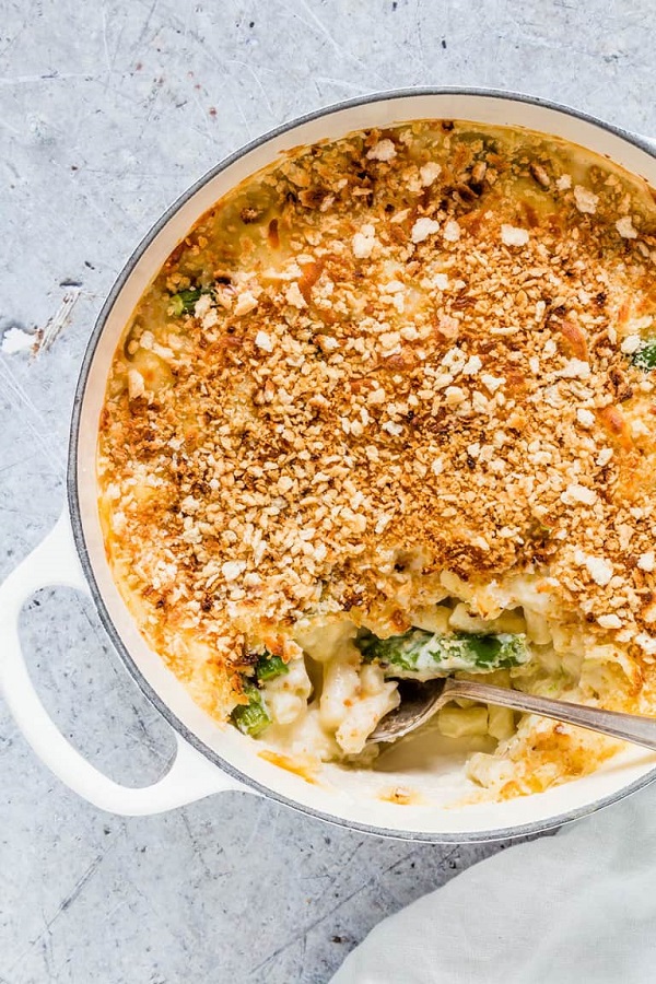 Asparagus macaroni cheese in a white casserole dish with a serving spoon