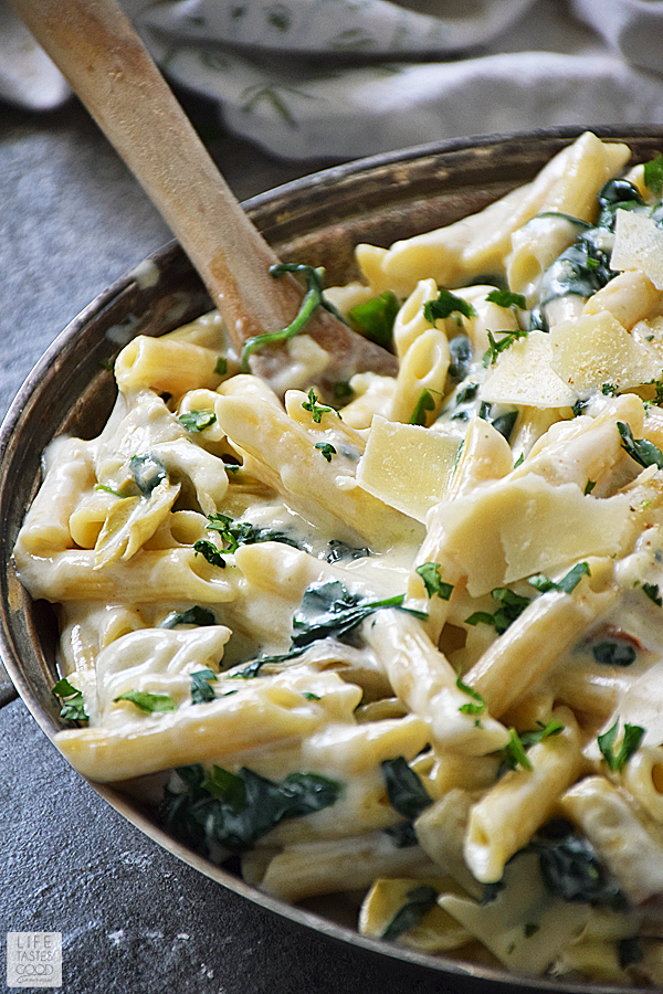 Spinach Artichoke Pasta Recipe in a skillet with a wooden spoon