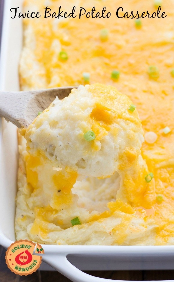 Twice baked potato casserole in a white casserole dish and a wooden spoon