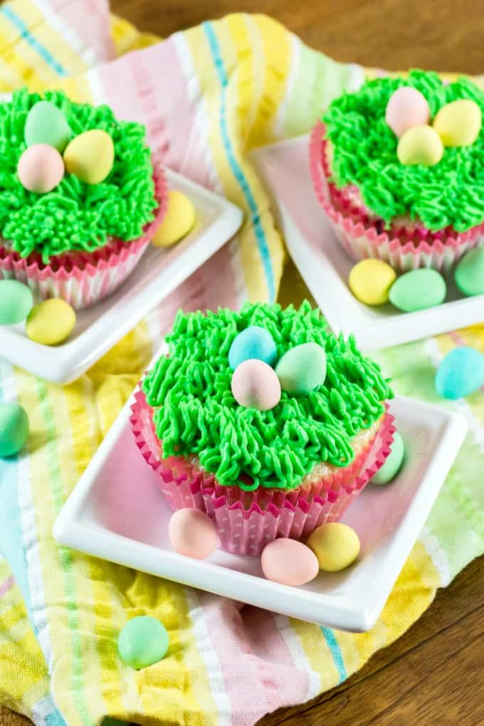 Easter Cupcakes on little white dishes with Easter eggs. 