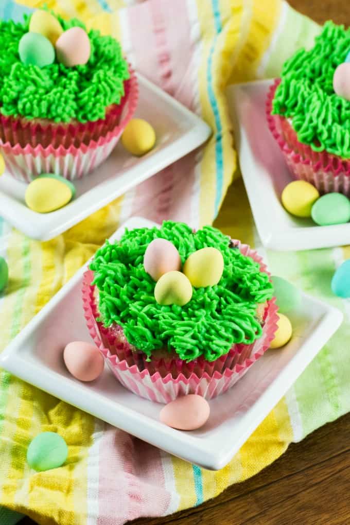 Easter Cupcakes on little white dishes with Easter eggs. 